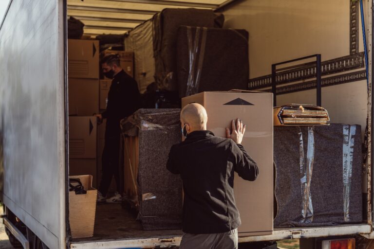 Two men arranging large boxes inside the truck in the concept of 'How to Choose the Best Home Removals Company for a Smooth Move to Chiswick'.